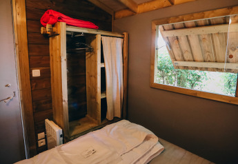 Indretning af et soveværelse i Lodge Premium-hytte på Camping Seasonova Ile de Ré med åbent vindue.