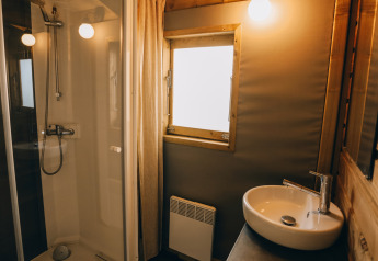 Bagno moderno nella Lodge Premium al Camping Seasonova Ile de Ré in Francia, con doccia e lavabo tondo.