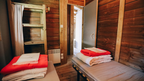 Binnenzicht van Lodge Premium in Camping Seasonova Ile de Ré, Frankrijk, met twee bedden en beddengoed.