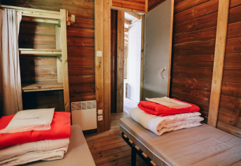 Indretning af et træværelse i Lodge Premium, Camping Seasonova Ile de Ré, med to senge og sengetøj.