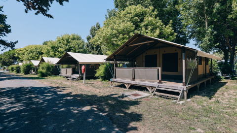 Safari-tenten van Slow Lodge op Camping Seasonova Ile de Ré, Frankrijk, omringd door bomen en zon.