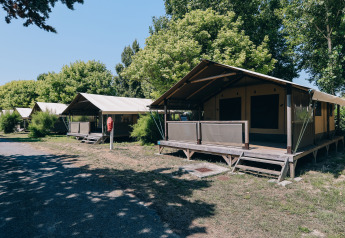Safari-tenten van Slow Lodge op Camping Seasonova Ile de Ré, Frankrijk, omringd door bomen en zon.
