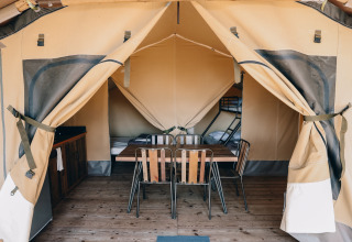 Tienda safari Slow Lodge en Camping Seasonova Ile de Ré en Francia, con mesa, sillas y camas en el interior.