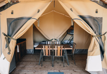 Tienda safari Slow Lodge en Camping Seasonova Ile de Ré en Francia, con mesa, sillas y camas en el interior.