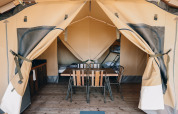 Tenda safari Slow Lodge al Camping Seasonova Ile de Ré in Francia, con tavolo, sedie e letti all'interno.
