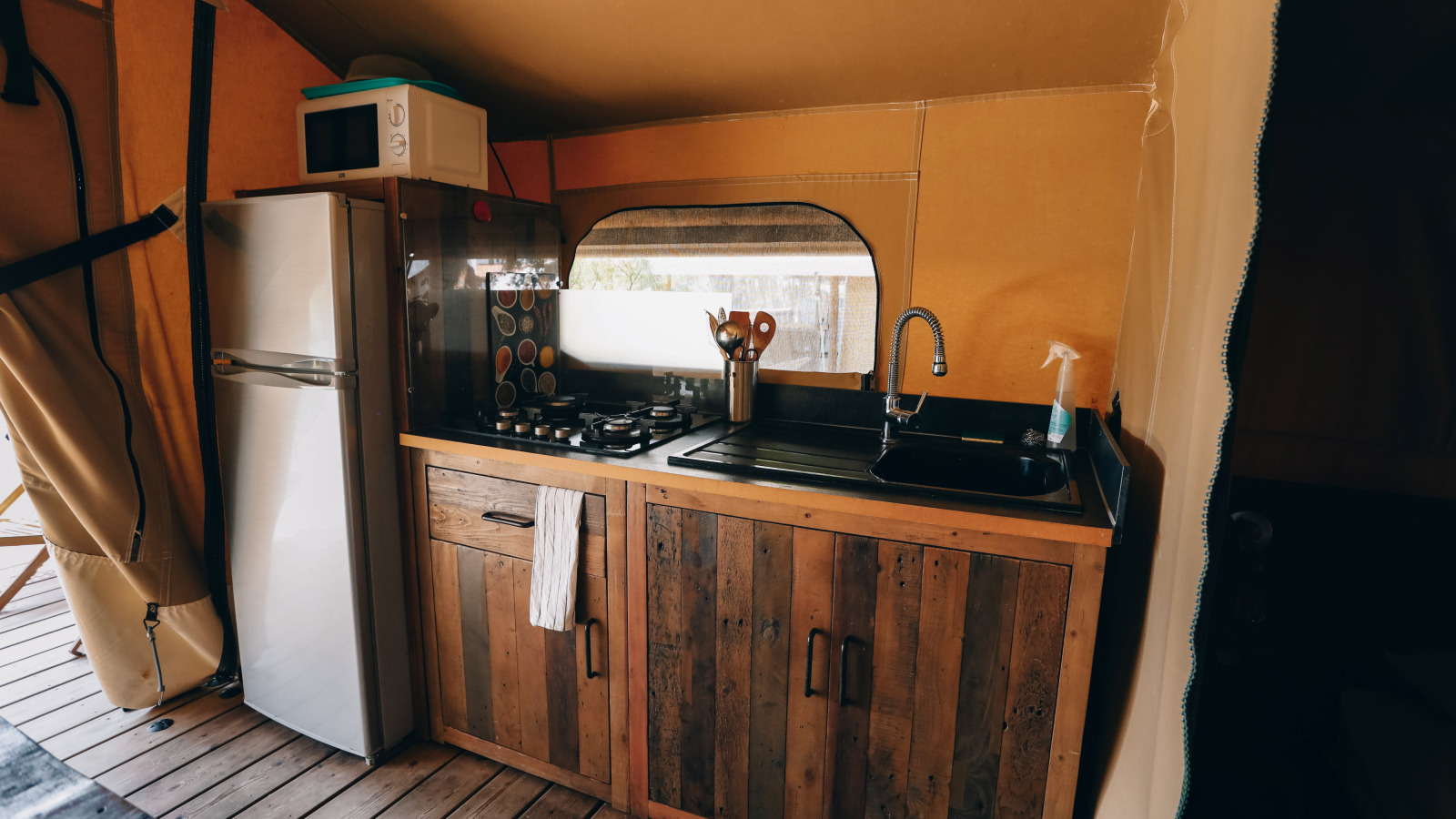 Keukengedeelte in een safaritent bij Slow Lodge, Camping Seasonova Ile de Ré, met koelkast en gasfornuis.