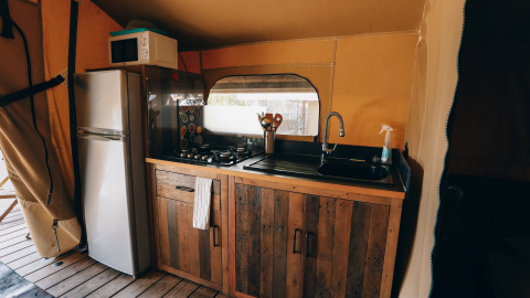 Keukenhoek in een safaritent bij Slow Lodge, Camping Seasonova Ile de Ré, met koelkast en gasfornuis.