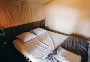 Vista interior de una cama cómoda en una tienda safari Slow Lodge en Camping Seasonova Ile de Ré, Francia.