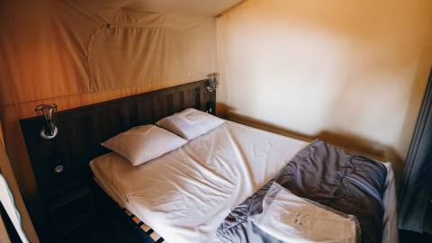 Vista interna di un letto accogliente nella tenda safari Slow Lodge al Camping Seasonova Ile de Ré in Francia.