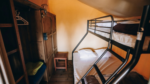 Interieur van een safari tent Slow Lodge met stapelbedden en houten kast op Camping Seasonova Ile de Ré, Frankrijk.