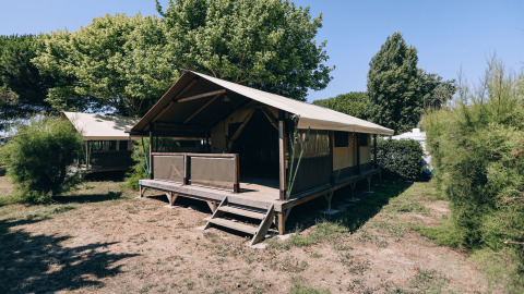 Foto van een safaritent genaamd Slow Lodge op Camping Seasonova Ile de Ré in Frankrijk, tussen bomen.
