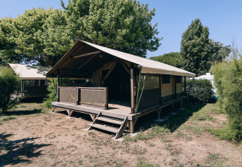 Foto van een safaritent genaamd Slow Lodge op Camping Seasonova Ile de Ré in Frankrijk, tussen bomen.