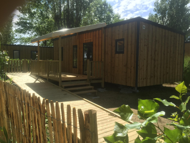 Casa móvil accesible con rampa y terraza de madera, adecuada para personas discapacitadas en zona verde.