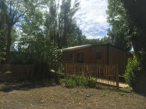 Mobile home for disabled at Camping Seasonova Ile de Ré, France, surrounded by trees and wooden fence.