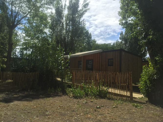 Casa móvil adaptada para discapacitados en Camping Seasonova Ile de Ré, Francia, entre árboles y valla.