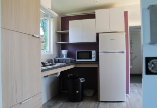 Cocina compacta con nevera, microondas y diseño accesible en un móvil home para discapacitados en Francia.