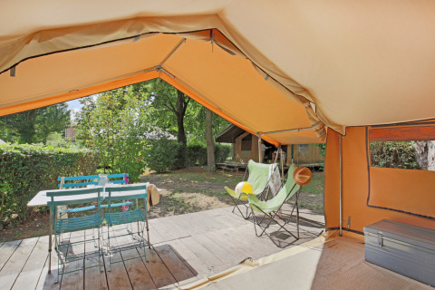 Vista interior de una tienda Safari Bungalow tent Classic con terraza, mesa, sillas y zona verde.