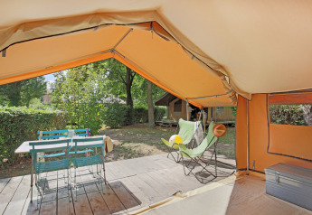 Vista interior de una tienda Safari Bungalow tent Classic con terraza, mesa, sillas y zona verde.