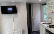 Modernes Interieur der Glamping Coco Sweet Lodge im Bospark De Brenkberg, Niederlande, mit Küche und TV.