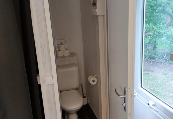 Small bathroom with toilet and window at Glamping Coco Sweet, Bospark De Brenkberg, Netherlands.