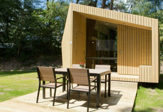 Casa pequeña moderna Trek-in en Beerze Bulten, Países Bajos, con terraza de madera y muebles de jardín.