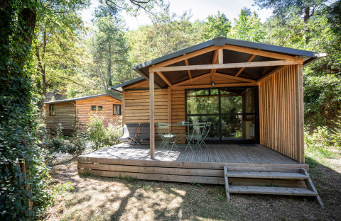 Cabaña Chalet Evasion en Huttopia Gorges du Tarn, Francia, con terraza de madera y vegetación.