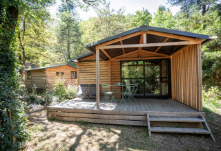 Cabaña Chalet Evasion en Huttopia Gorges du Tarn, Francia, con terraza de madera y vegetación.