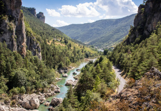 Langs de rivier bij Huttopia Gorges du Tarn in Occitanië, Frankrijk, omgeven door groene heuvels en rotsen.