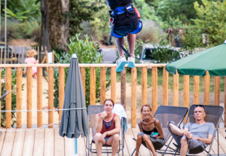Een kind op de zipline boven het zwembad, bekeken door mensen bij Huttopia Gorges du Tarn in Occitanië, Frankrijk.