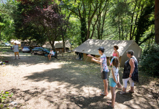 Familie geniet van buitenspelen bij tenten op camping Huttopia Gorges du Tarn in Occitanië, Frankrijk.