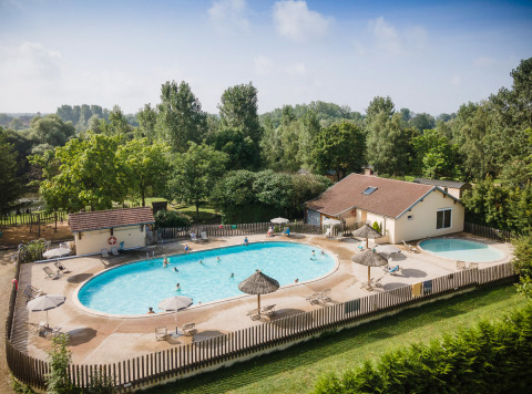 Piscina exterior con tumbonas y sombrillas en Huttopia La Plage Blanche en Bourgogne-Franche-Comté, Francia.