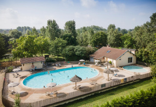 Udendørs poolområde med liggestole og parasoller på Huttopia La Plage Blanche i Bourgogne-Franche-Comté.