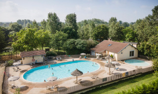 Piscina exterior con tumbonas y sombrillas en Huttopia La Plage Blanche en Bourgogne-Franche-Comté, Francia.