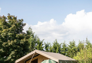 Grote safaritent met terras en stoelen in het groen bij vakantiepark Huttopia La Plage Blanche in Frankrijk.