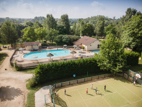 Luftaufnahme vom Ferienpark Huttopia La Plage Blanche in Frankreich mit Pool, Sportplatz und viel Grün.