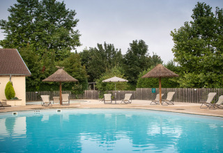 Swimmingpool med liggestole og parasoller i ferieparken Huttopia La Plage Blanche i Bourgogne-Franche-Comté, Frankrig.