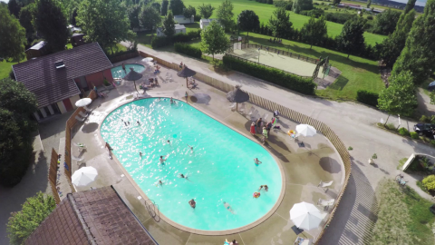 Vista aérea de una piscina y área de recreo con visitantes en Huttopia La Plage Blanche, Bourgogne-Franche-Comté, Francia.