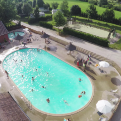 Vista aérea de una piscina y área de recreo con visitantes en Huttopia La Plage Blanche, Bourgogne-Franche-Comté, Francia.