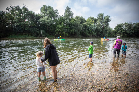 Famiglie si divertono pescando e facendo kayak al parco vacanze Huttopia La Plage Blanche in Francia.