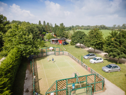 Kinderen spelen op een sportveld, omgeven door bomen en auto's, bij Huttopia La Plage Blanche in Frankrijk.