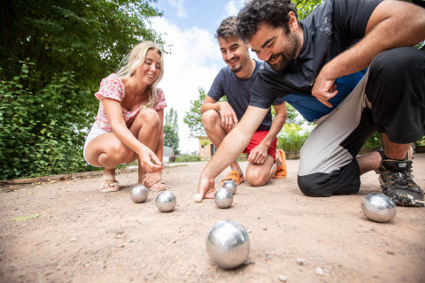 Tres personas disfrutan jugando a la petanca en Huttopia La Plage Blanche en Bourgogne-Franche-Comté, Francia.