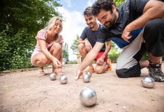 Tres personas disfrutan jugando a la petanca en Huttopia La Plage Blanche en Bourgogne-Franche-Comté, Francia.