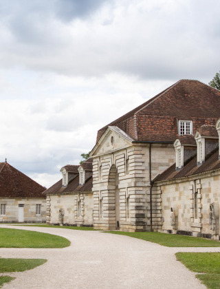 Edificios históricos de piedra con tejados rojos cerca de Ounans, Bourgogne-Franche-Comté, Francia, cielo nublado.