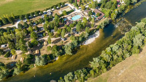 Vista aérea del parque de vacaciones Huttopia La Plage Blanche con piscina, árboles y río en Bourgogne-Franche-Comté, Francia.