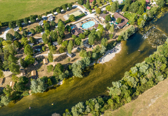 Luchtfoto van vakantiepark Huttopia La Plage Blanche met zwembad, bomen en rivier in Bourgogne-Franche-Comté, Frankrijk.