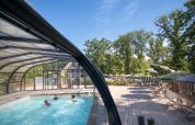 Udendørs pool og terrasse ved Huttopia Wattwiller feriepark omgivet af træer i Grand Est, Frankrig.