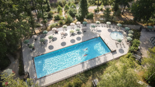 Luchtfoto van het zwembad met ligstoelen en parasols bij Huttopia Wattwiller vakantiepark in Grand Est, Frankrijk.