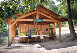 Bezoekers doen de afwas onder een houten afdak in Huttopia Wattwiller vakantiepark, Grand Est, Frankrijk.