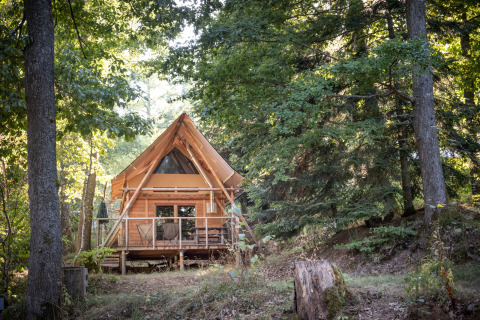 Gemütliche Holzhütte im Wald im Ferienpark Huttopia Wattwiller, Grand Est, Frankreich, zwischen Bäumen.
