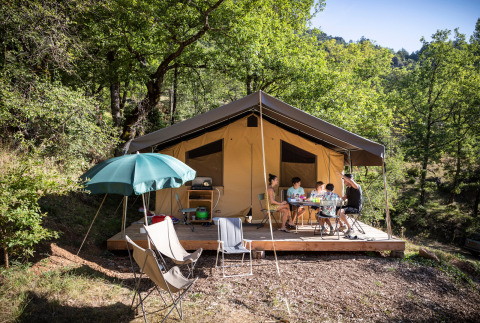 Famille prenant un repas devant la tente safari Tent Sweet à Huttopia Gorges du Tarn, France.